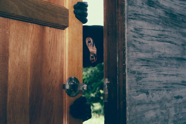 Un ladrón acechando en la puerta de una casa